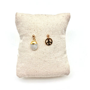 2 earrings on a cushion, one crystal drop, one peace sign charm