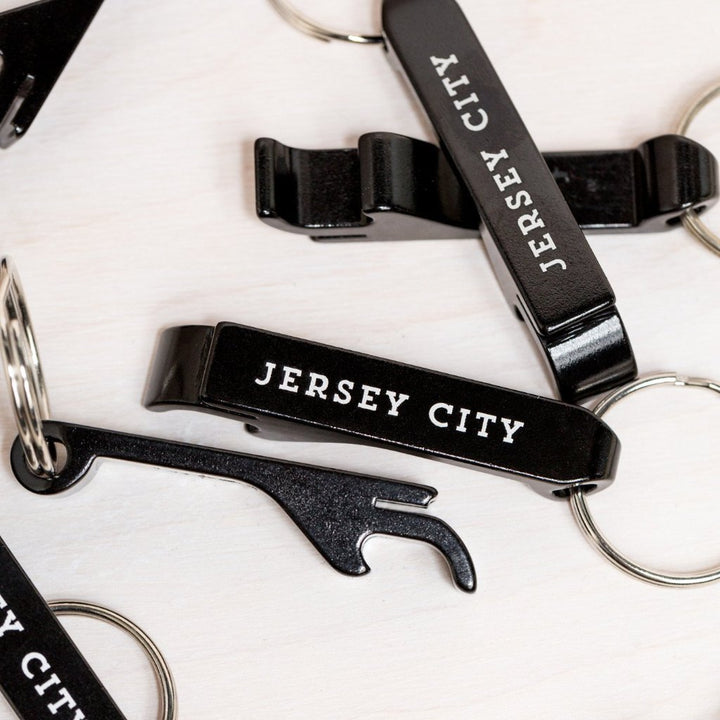 Black Jersey City bottle opener keychain with white text on a metal key ring by Kanibal Co.