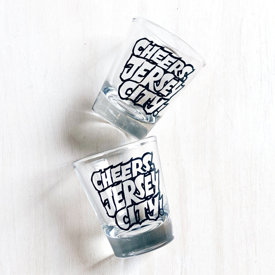 Two clear shot glasses with Cheers Jersey City black text design on white background Jersey City shot glass