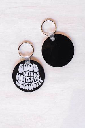 Black circular Jersey City souvenir keychain with white text good things happen in Jersey City