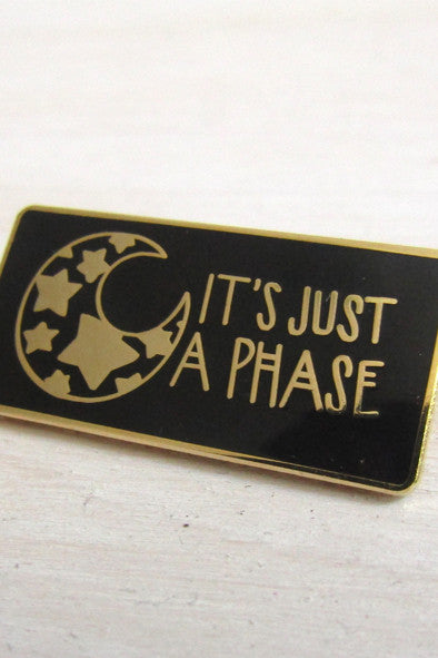 black and gold rectangle pin with illustration of mood with stars inside it.