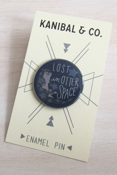 blue round pin with illustration of otter on cardstock